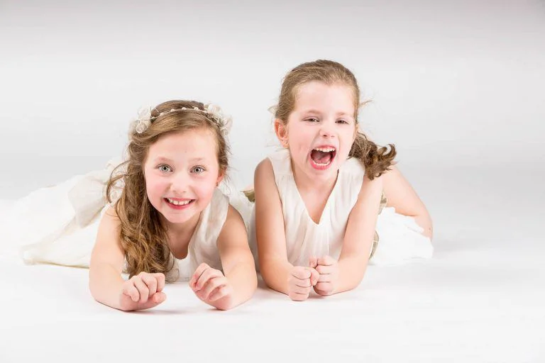 Fotografía de Comunión en Familia - Fotógrafo de Tarragona Fotografia de dos hermanas partiendose de risa para su reportaje de comunion en estudio, por el fotografo Juan Segovia en Tarragona