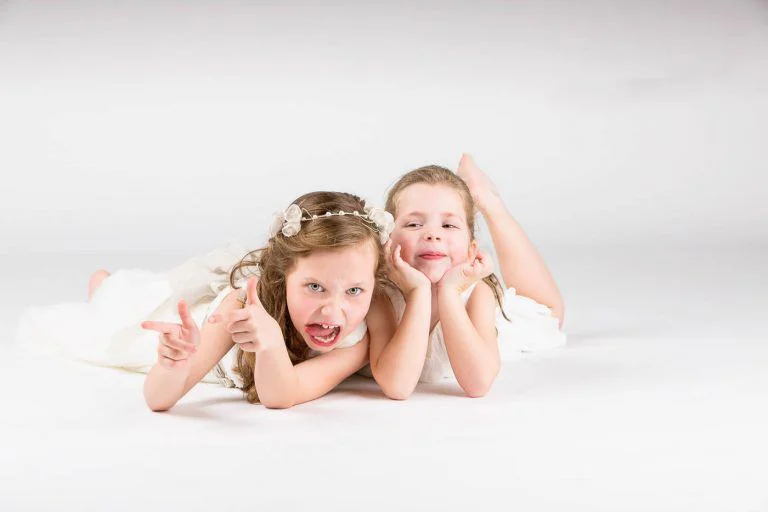 Fotografía de Comunión en Familia - Fotógrafo de Tarragona Fotografia de dos hermanas tumbadas en el suelo para su reportaje de comunion en estudio, por el fotografo Juan Segovia en Tarragona
