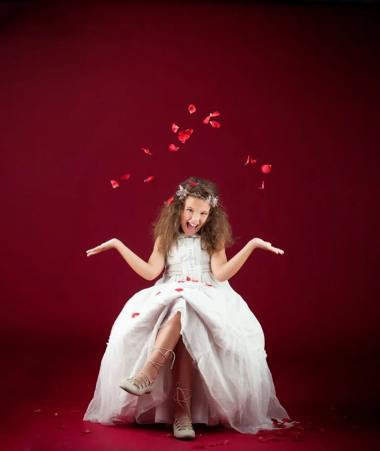 Galería de Fotos de Niñas de Comunión en Estudio - Fotógrafo de Tarragona Fotografía de comunión en estudio de Olivia lanzando pétalos rojos, por el fotógrafo Juan Segovia en Tarragona