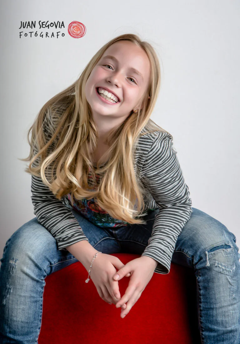 Galería de Fotos de Niñas de Comunión en Estudio - Fotógrafo de Tarragona Retrato fotográfico en estudio de una niña sentada riendo por Juan Segovia, fotógrafo en Tarragona
