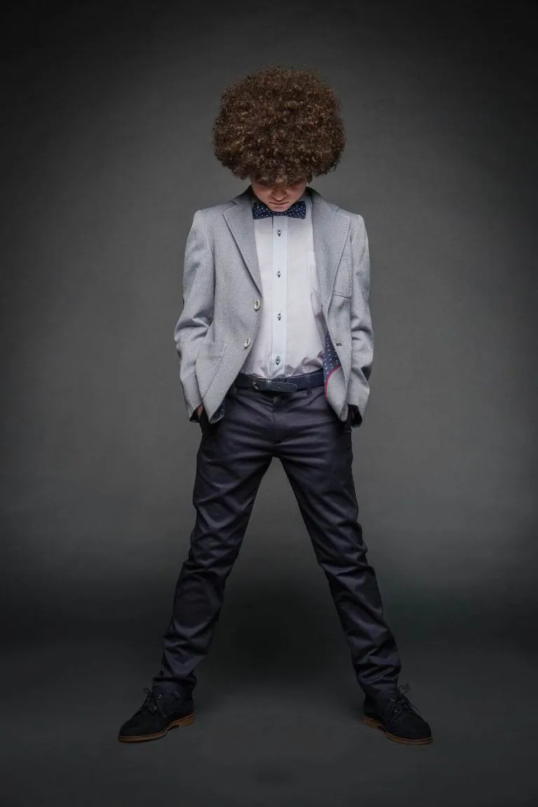 Galería de Fotos de Niños de Comunión en Estudio - Fotógrafo de Tarragona Fotografia de Max con pelo afro mirando al suelo para su reportaje de comunion en el estudio de Juan Segovia en Tarragona