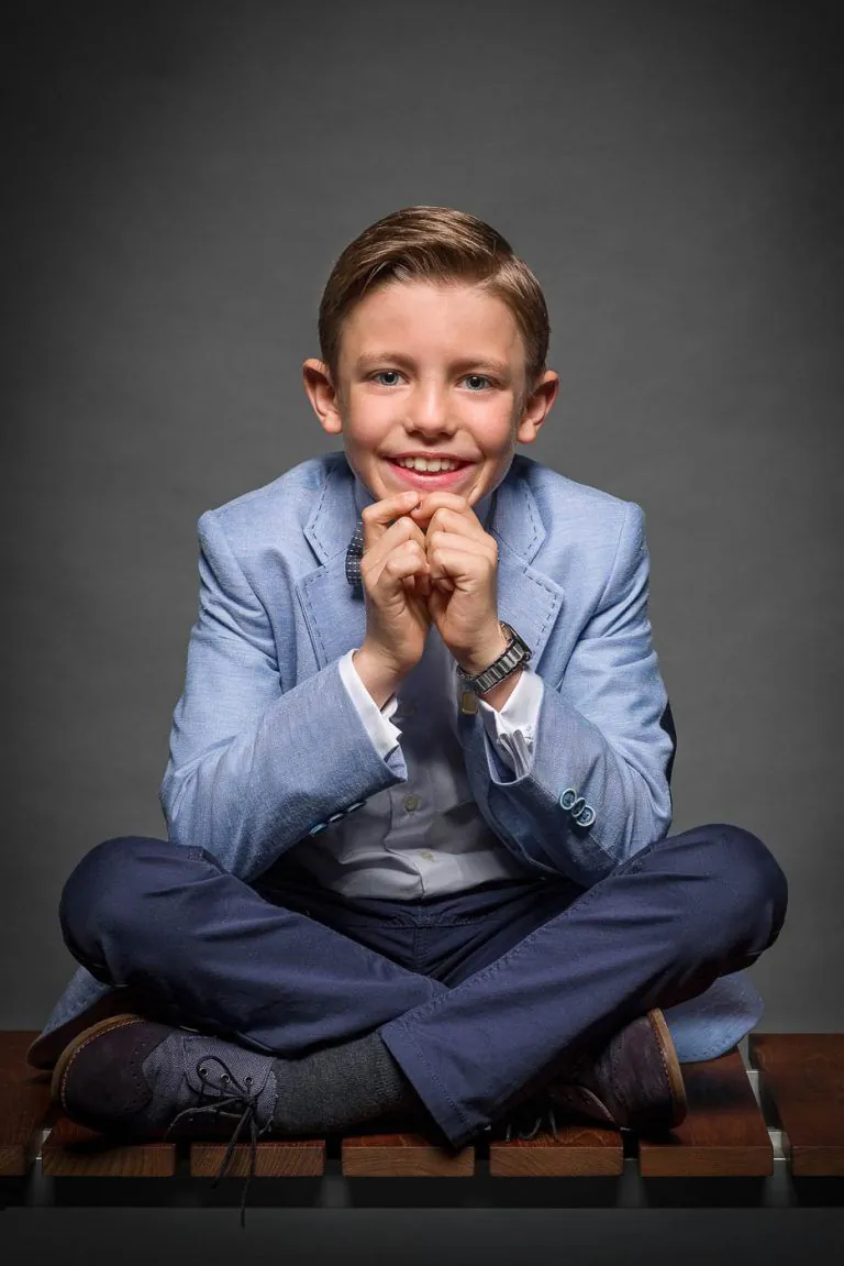 Galería de Fotos de Niños de Comunión en Estudio - Fotógrafo de Tarragona Fotografia de un nino con americana azul sentado sobre un banco para su reportaje de comunion en el estudio de Juan Segovia en Tarragona