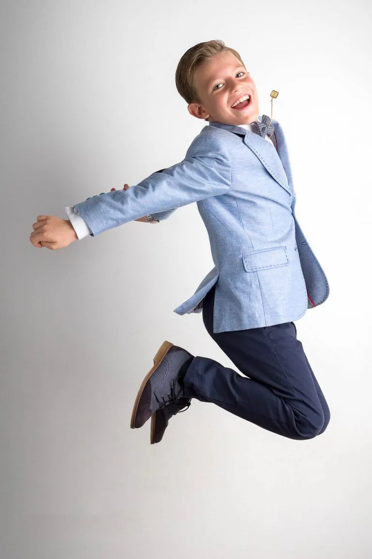 Galería de Fotos de Niños de Comunión en Estudio - Fotógrafo de Tarragona Fotografia de un nino con americana saltando y riendo para su reportaje de comunion en el estudio de Juan Segovia en Tarragona