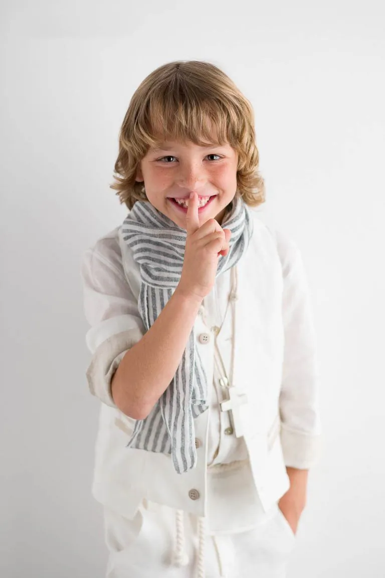 Galería de Fotos de Niños de Comunión en Estudio - Fotógrafo de Tarragona Fotografia de un nino con el dedo delante de su boca para su reportaje de comunion en el estudio de Juan Segovia en Tarragona