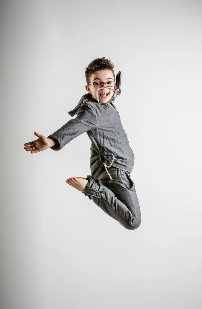 Galería de Fotos de Niños de Comunión en Estudio - Fotógrafo de Tarragona Fotografia de un nino con gafas saltando para su reportaje de comunion en el estudio de Juan Segovia en Tarragona