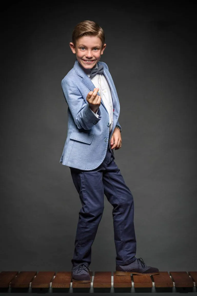 Galería de Fotos de Niños de Comunión en Estudio - Fotógrafo de Tarragona Fotografia de un nino con pajarita bailando sobre un banco para su reportaje de comunion en el estudio de Juan Segovia en Tarragona