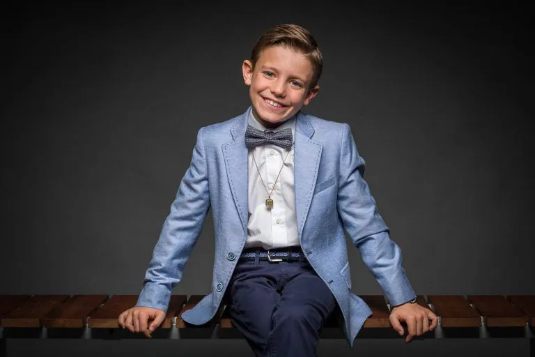 Galería de Fotos de Niños de Comunión en Estudio - Fotógrafo de Tarragona Fotografia de un nino con pajarita sentado sobre un banco para su reportaje de comunion en el estudio de Juan Segovia en Tarragona