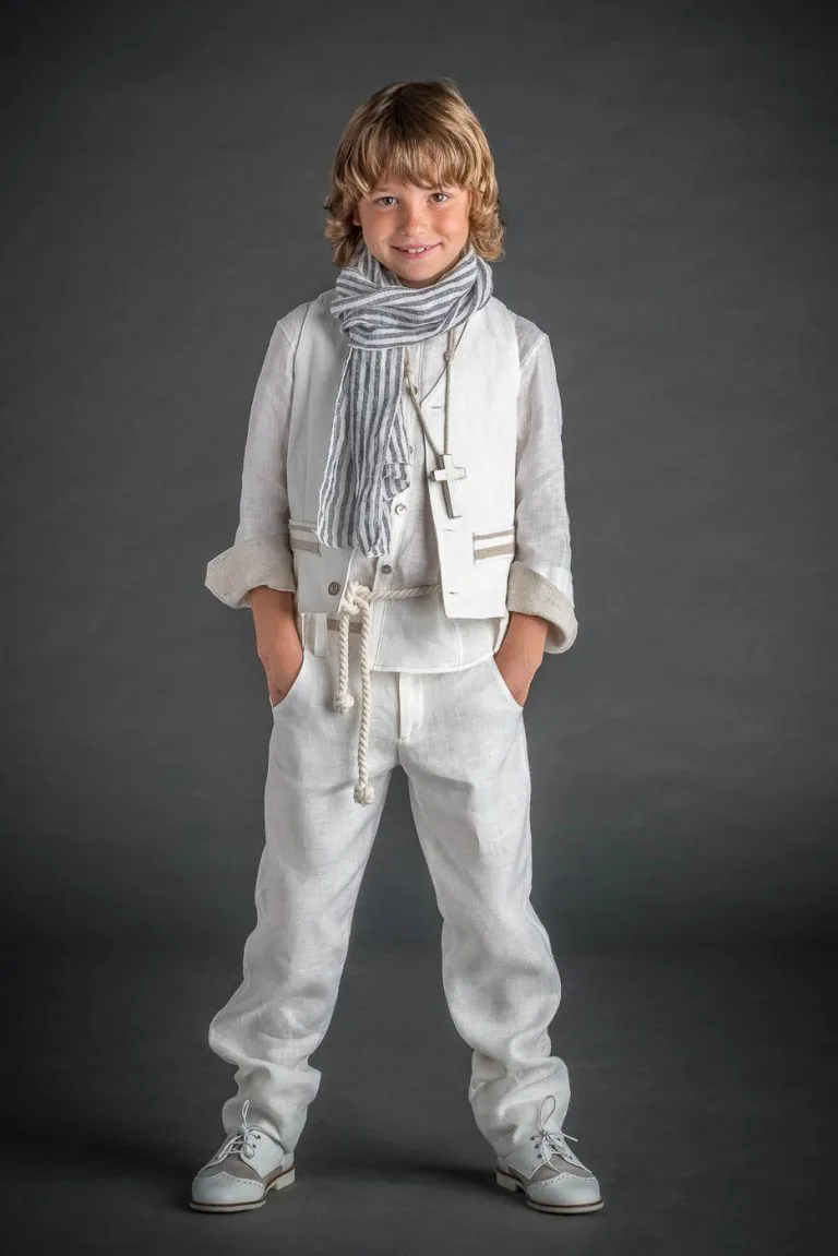 Galería de Fotos de Niños de Comunión en Estudio - Fotógrafo de Tarragona Fotografia de un nino con traje blanco fulard y manos en los bolsillos para su reportaje de comunion en el estudio de Juan Segovia en Tarragona