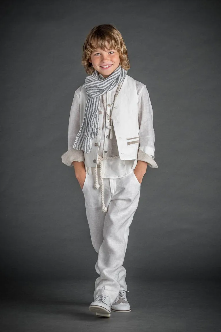 Galería de Fotos de Niños de Comunión en Estudio - Fotógrafo de Tarragona Fotografia de un nino con traje blanco y fulard caminando para su reportaje de comunion en el estudio de Juan Segovia en Tarragona