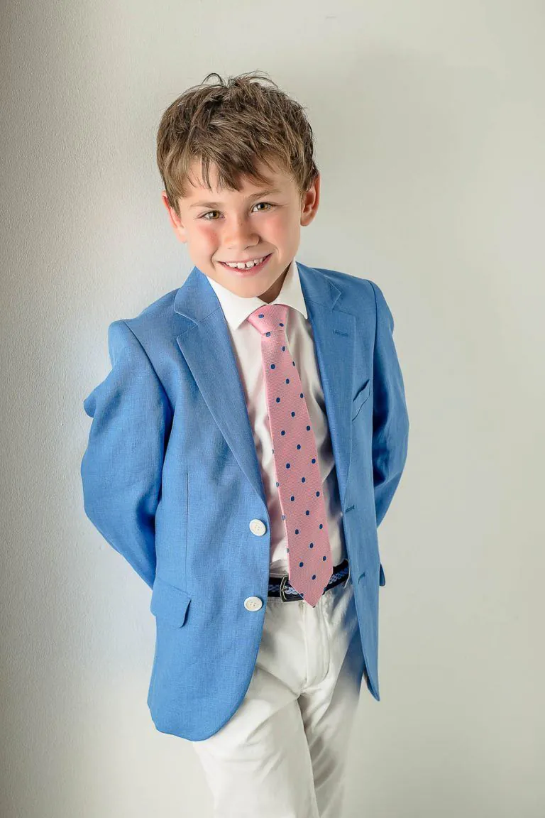 Galería de Fotos de Niños de Comunión en Estudio - Fotógrafo de Tarragona Fotografia de un nino de comunion con americana azul y corbata rosa para su reportaje de comunion en el estudio de Juan Segovia en Tarragona