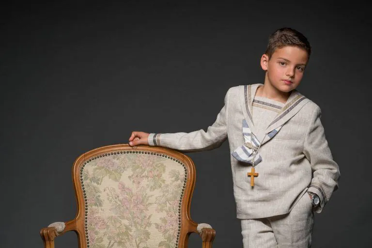 Galería de Fotos de Niños de Comunión en Estudio - Fotógrafo de Tarragona Fotografia de un nino de marinero apoyado en un sillon para su reportaje de comunion en el estudio de Juan Segovia en Tarragona
