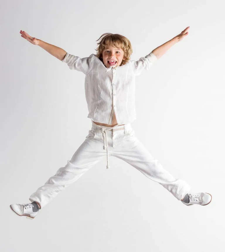 Galería de Fotos de Niños de Comunión en Estudio - Fotógrafo de Tarragona Fotografia de un nino haciendo un X en el aire para su reportaje de comunion en el estudio de Juan Segovia en Tarragona