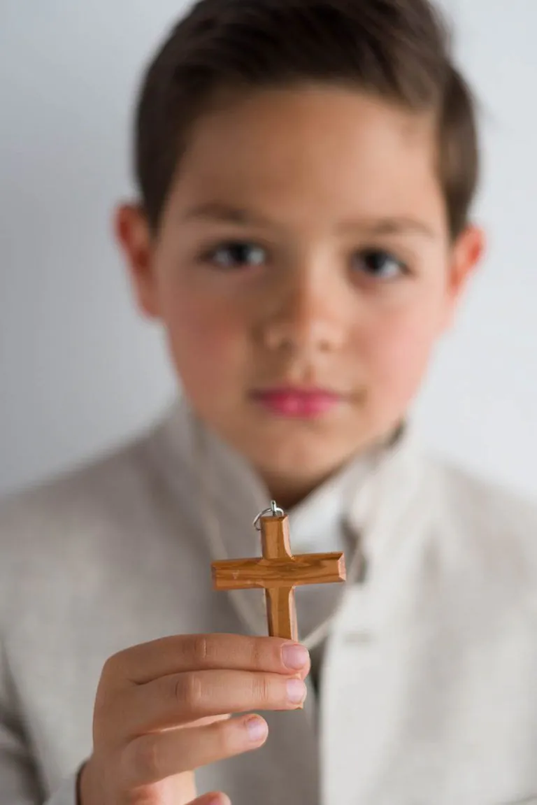 Galería de Fotos de Niños de Comunión en Estudio - Fotógrafo de Tarragona Fotografia de un nino mostrando su crucifijo para su reportaje de comunion en el estudio de Juan Segovia en Tarragona