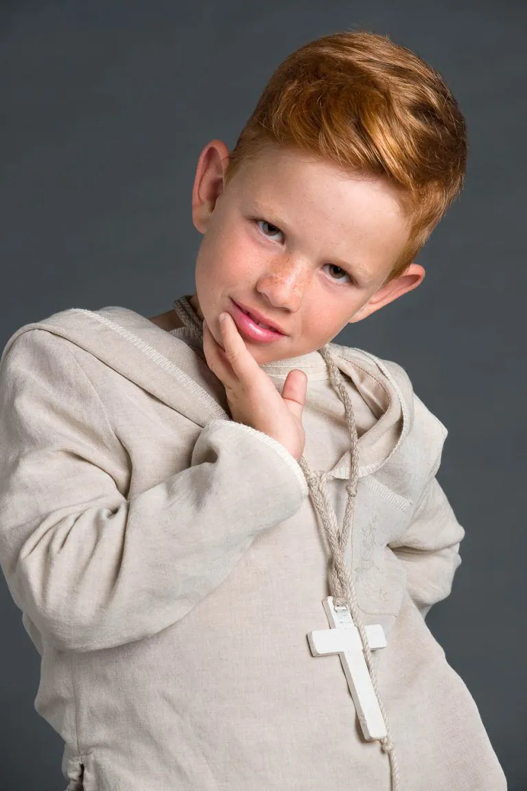 Galería de Fotos de Niños de Comunión en Estudio - Fotógrafo de Tarragona Fotografia de un nino pelirojo apoyando su barbilla sobre una mano para su reportaje de comunion en el estudio de Juan Segovia en Tarragona