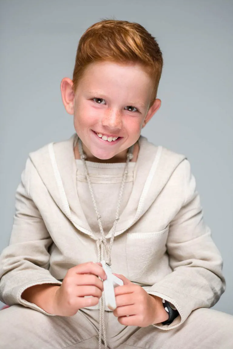 Galería de Fotos de Niños de Comunión en Estudio - Fotógrafo de Tarragona Fotografia de un nino pelirojo sujetando su crucifijo para su reportaje de comunion en el estudio de Juan Segovia en Tarragona