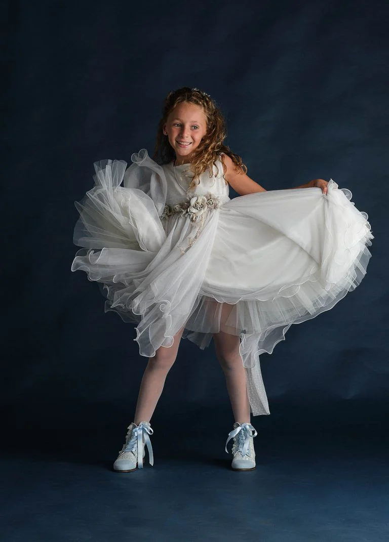 Galería de Fotos de Niñas de Comunión en Estudio - Fotógrafo de Tarragona Fotografia de una nina bailando con chaqueta tejana para su reportaje de comunion en el estudio del fotografo Juan Segovia en Tarragona