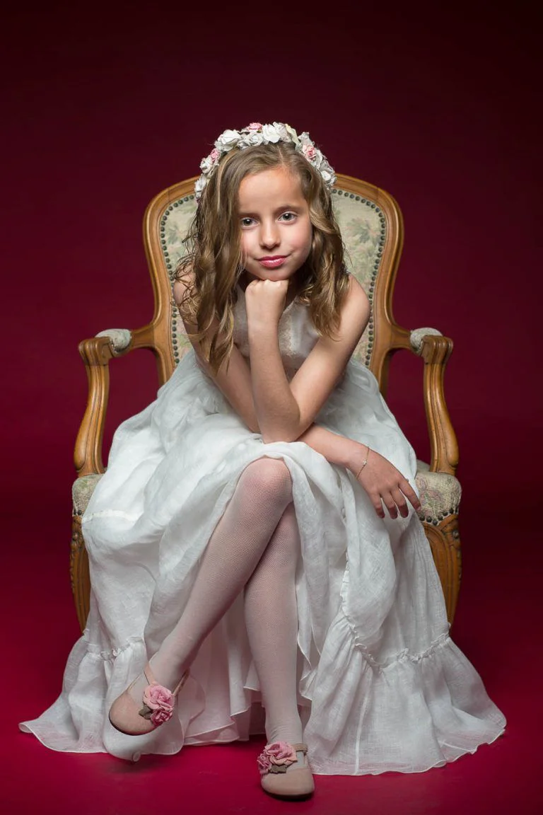 Galería de Fotos de Niñas de Comunión en Estudio - Fotógrafo de Tarragona Fotografia de una nina con la barbilla apollada en su puno para su reportaje de comunion en el estudio del fotografo Juan Segovia en Tarragona