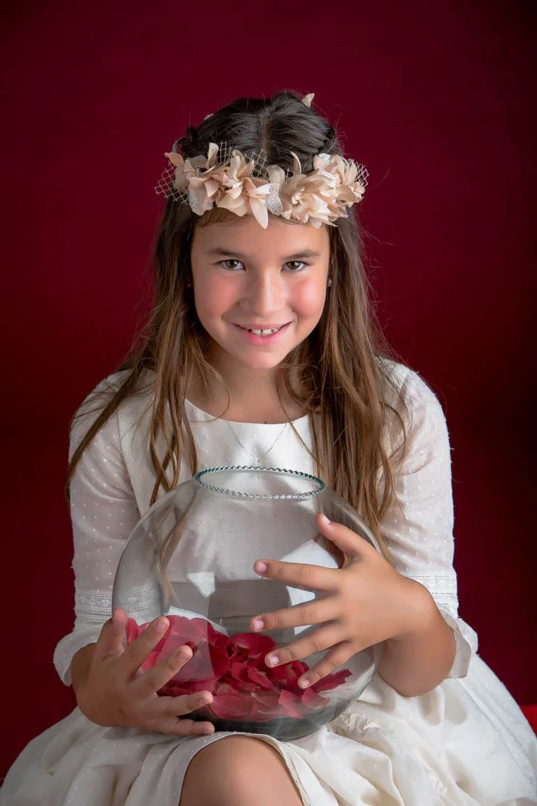 Galería de Fotos de Niñas de Comunión en Estudio - Fotógrafo de Tarragona Fotografia de una nina con pecera petalos para su reportaje de comunion en el estudio del fotografo Juan Segovia en Tarragona