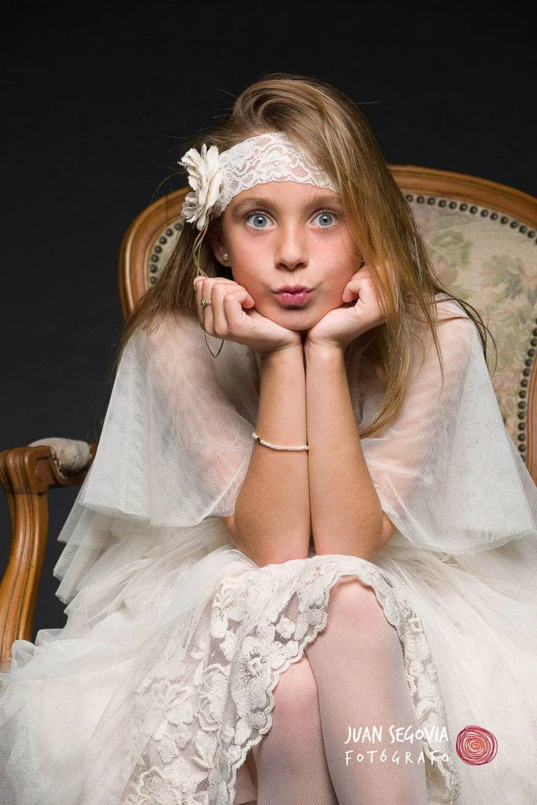 Galería de Fotos de Niñas de Comunión en Estudio - Fotógrafo de Tarragona Fotografia de una nina sentada con expresion de sorpresa para su reportaje de comunion en el estudio del fotografo Juan Segovia en Tarragona