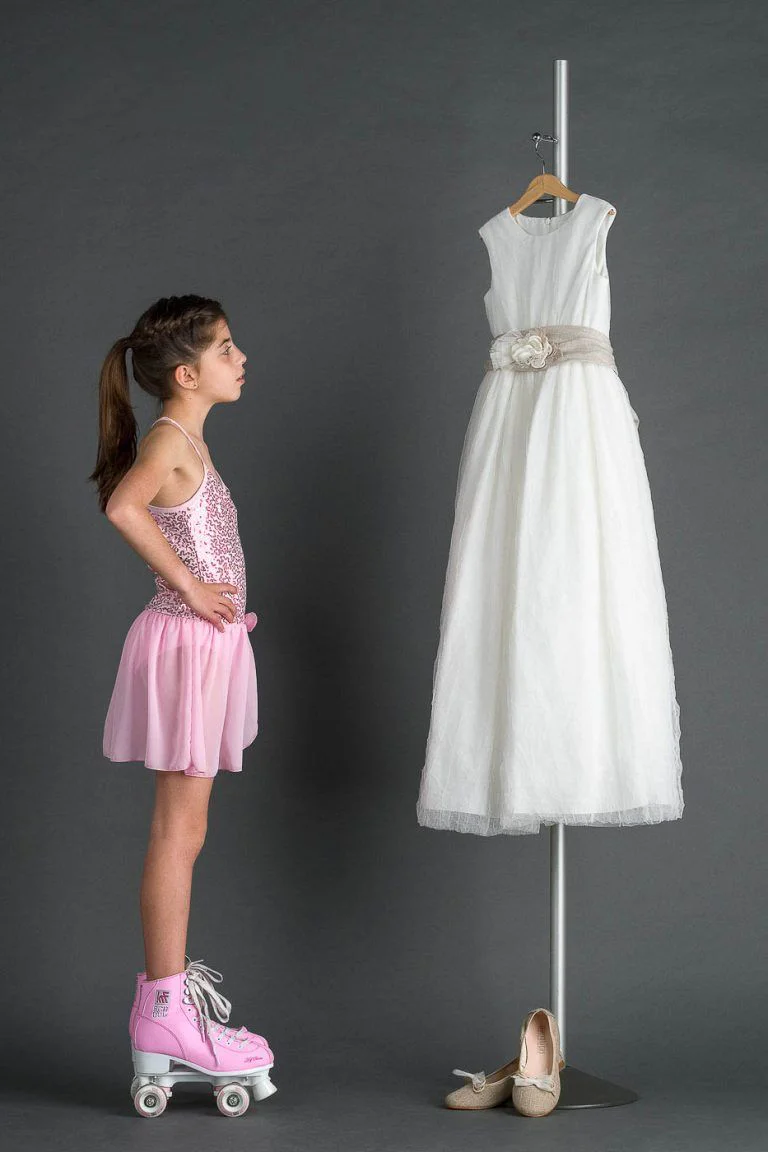 Galería de Fotos de Niñas de Comunión en Estudio - Fotógrafo de Tarragona Fotografia de una nina sobre patines y vestido rosa para su reportaje de comunion en el estudio del fotografo Juan Segovia en Tarragona